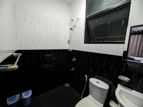 a black and white bathroom with a toilet and a sink at Big John Hotel in Dehiwala