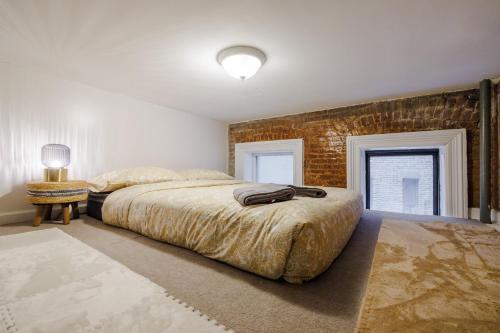 a bedroom with a large bed and a brick wall at Experience the Vibrant Energy of City Living in New York