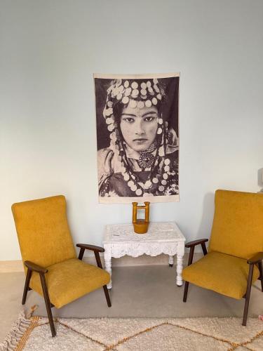 two chairs and a table with a painting on the wall at Riad lunja in Marrakech