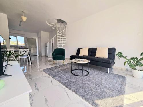 a living room with a black couch and a table at 2BD Garden Apartment in Paphos City