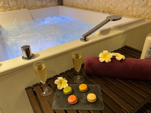 a bath tub with two glasses of wine and some donuts at Le Trophée Boutique Hôtel Spa- La Loggia Appart'hôtel in Deauville
