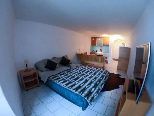 a bedroom with a large bed and a kitchen at Private apartment with parking spot in the center in Flims
