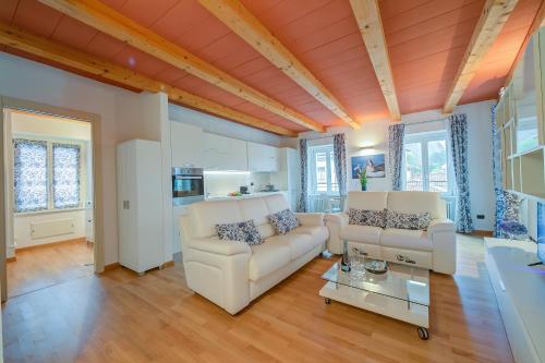 Concordia Apartment Laveno - Happy Rentals في لافينو: غرفة معيشة مع كنبتين بيضاء وطاولة