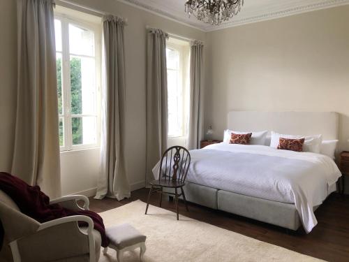 a bedroom with a bed and a chair and windows at La Pommeraie Champsecret in Champsecret