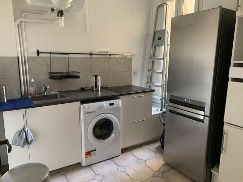 une cuisine avec un réfrigérateur et une machine à laver dans l'établissement Appartement les Lilas, aux Lilas