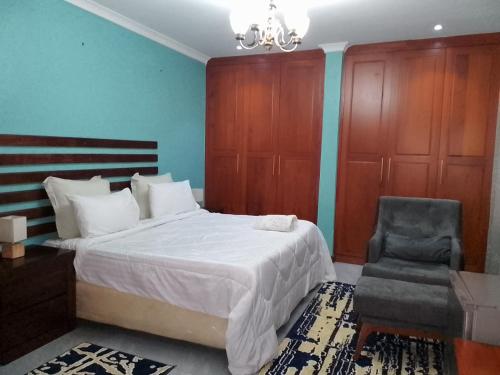 a bedroom with a large bed and a chair at ALIJAY APARTMENTS in Mumbwa