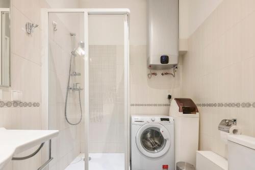 ein weißes Bad mit einer Waschmaschine und einer Dusche in der Unterkunft Main street apartments SELF CHECK IN 24/7 by H&H in Vilnius