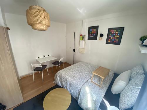 une petite chambre avec un lit et une table dans l'établissement Cozy Projector Home, 6 Min to Metro, à Aubervilliers