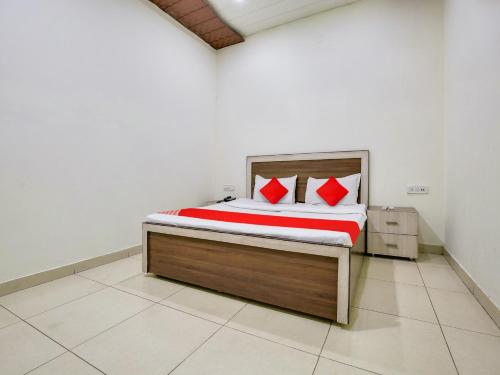 a bedroom with a large bed with red pillows at Super OYO Collection O Hotel White Prime in Phagwāra