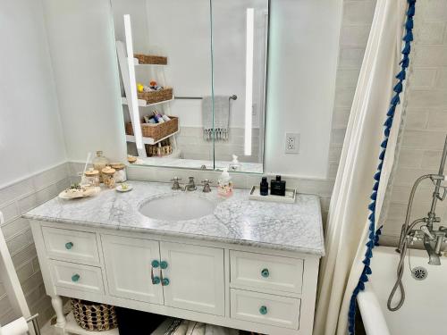 a white bathroom with a sink and a mirror at Balboa Island Beach Cottage with Golf Cart in Newport Beach