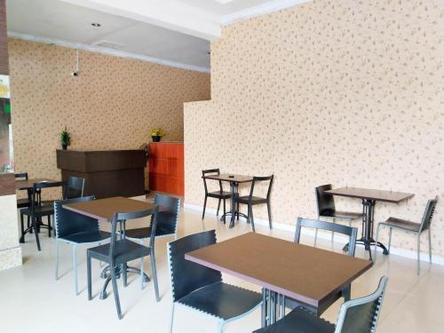 uma sala de jantar com mesas e cadeiras e uma parede em Hotel Labuhan Raya em Medan