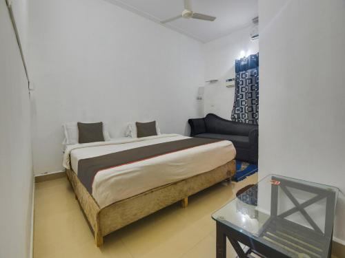 Collection O Goa Savera Holiday Homes في Nerul: غرفة نوم بسرير واريكة وطاولة