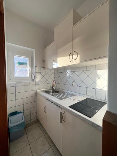 a kitchen with white cabinets and a sink and a window at Apartments Antic 1 in Pješčana Uvala