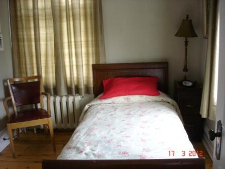1 dormitorio con cama con almohada roja y silla en Le Gîte des Soeurs, en Saint-Luc-de-Vincennes