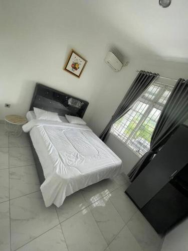 a bedroom with a bed with white sheets and a window at Puncak villa in Puncak