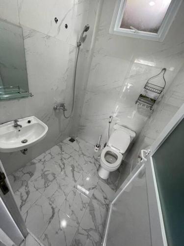 a white bathroom with a toilet and a sink at Puncak villa in Puncak