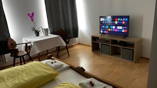 - un salon avec une télévision, une table et un lit dans l'établissement Gasthof Zur Post - Inning, à Inning am Ammersee