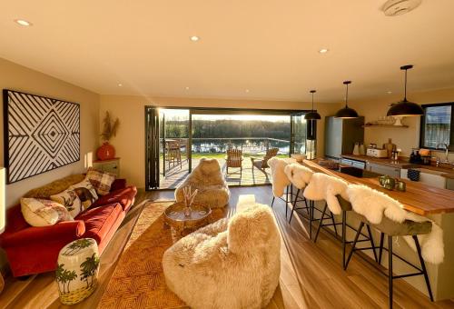 a living room with a couch and chairs and a kitchen at Zen Jungle Retreat - Log Cabin Stays, Transformational Retreats & Holistic Wellness near Bude - A 40 Acre Retreat with 5 Lakes, Woodland, Firepits, Bistro & Bars in Holsworthy