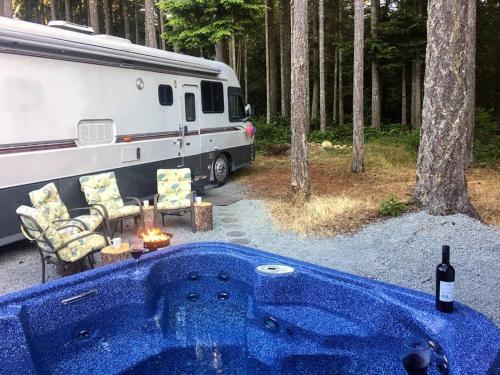 uma caravana estacionada ao lado de uma banheira azul em frente a uma tenda em The Great Escape - Shirley em Sooke