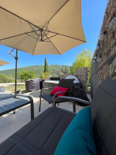 a patio with two chairs and an umbrella at LUVA d'Azur, Rez de villa LE RIOU - LE VALLON in Le Bar-sur-Loup