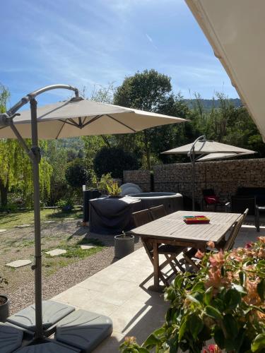 a patio with a table and an umbrella at LUVA d'Azur, Rez de villa LE RIOU - LE VALLON in Le Bar-sur-Loup