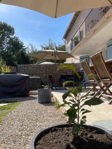 a patio with two chairs and a plant and an umbrella at LUVA d'Azur, Rez de villa LE RIOU - LE VALLON in Le Bar-sur-Loup