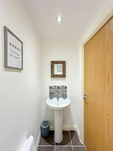 a bathroom with a white sink and a wooden door at Luxury 3 Bedroom House With FREE Parking in Dinnington