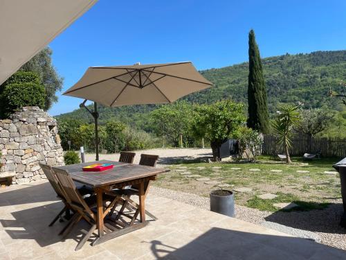 a wooden table with an umbrella on a patio at LUVA d'Azur, Rez de villa LE RIOU - LE VALLON in Le Bar-sur-Loup