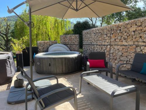 a patio with a hot tub and chairs and an umbrella at LUVA d'Azur, Rez de villa LE RIOU - LE VALLON in Le Bar-sur-Loup