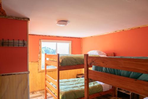 a room with three bunk beds and a window at Cabañas & Hostal Lefuco in Curacautín