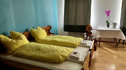 two beds with yellow sheets in a room with a table at Gasthof Zur Post - Inning in Inning am Ammersee
