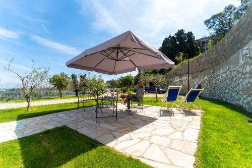 a woman sitting at a table under an umbrella at Nientemale Residence Napoli in Pozzuoli