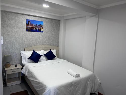 ein Schlafzimmer mit einem weißen Bett mit blauen Kissen in der Unterkunft Le palbot in Quatre Bornes