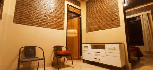 two chairs and a dresser in a room with a brick wall at Toraja Bungin Homestay in Rantepao