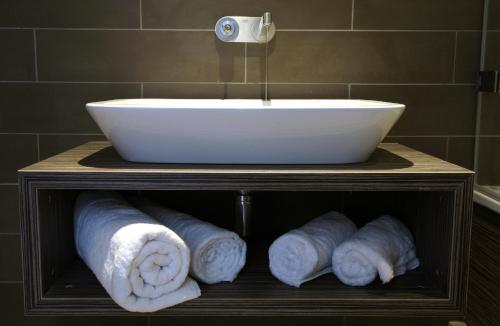 a bathroom with a sink and rolls of towels at Hotel Bosco in Kingston upon Thames