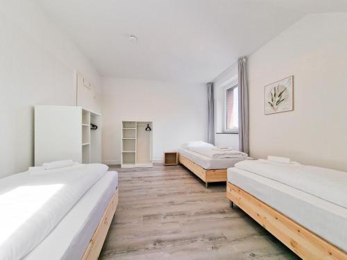 two beds in a room with white walls and wooden floors at Tolstov Apartments - 4 Room Apartments - 30 Min Messe DUS in Neuss