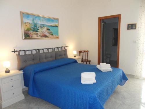 Un dormitorio con una cama azul con dos toallas encima. en Vincenzo Apartment, en Lampedusa