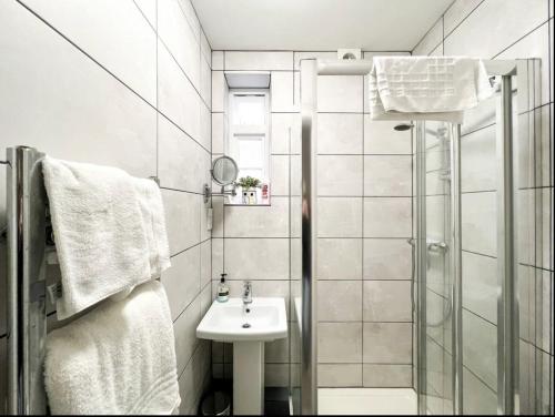 a white bathroom with a shower and a sink at Suitely Stays Berkeley Apartment 2 in Cheltenham