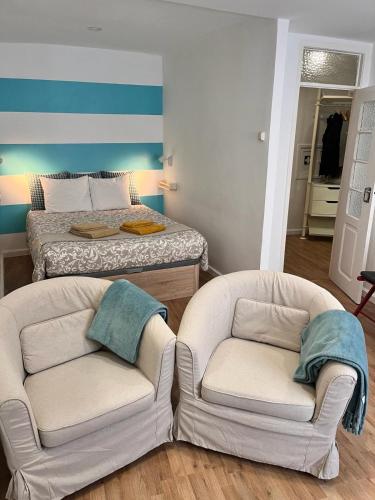 2 Stühle in einem Wohnzimmer mit einem Bett in der Unterkunft Casa Beco Do Castelo in Lissabon