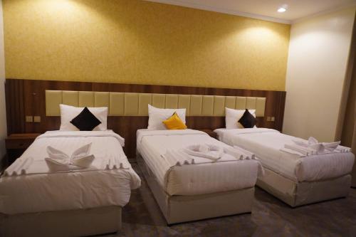 a bedroom with two beds and a headboard at اللؤلؤة الذهبي للشقق المخدومة in Medina