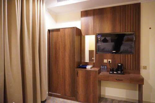 a hotel room with a desk and a flat screen tv at اللؤلؤة الذهبي للشقق المخدومة in Medina