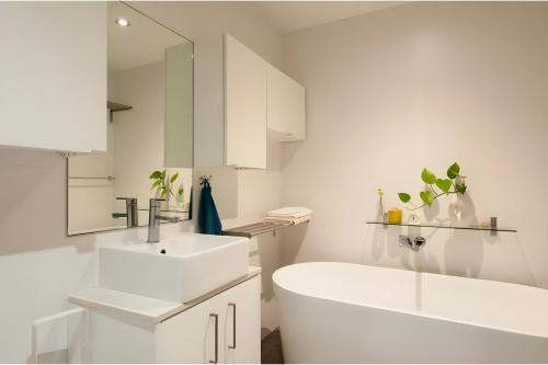 La salle de bains blanche est pourvue d'un lavabo et d'une baignoire. dans l'établissement XQ Collection Tiger's Place, Mascot, à Sydney