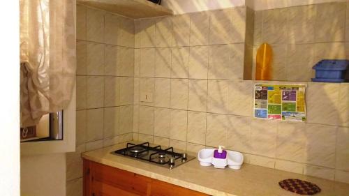 a kitchen counter with a stove and cups on it at Villetta Maestrale Cala Azzurra Favignana in Favignana