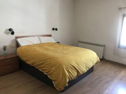 - une chambre avec un grand lit et une couverture jaune dans l'établissement Piso en casa de pueblo, à Almoster