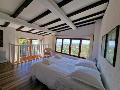 een slaapkamer met een groot bed in een kamer met ramen bij Villa Clarté Sète in Sète