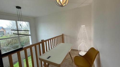 una mesa y una silla en una habitación con ventana en LA MAISON DE VIRGINIE, en Bénouville