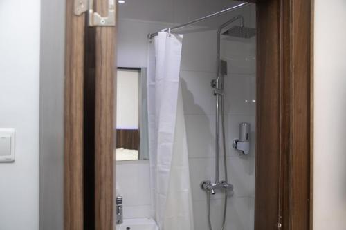 a bathroom with a shower with a white shower curtain at Baseville Hotel in Lagos