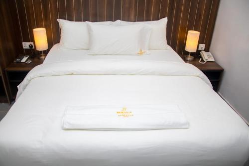 uma grande cama branca num quarto de hotel com duas lâmpadas em Baseville Hotel em Lagos