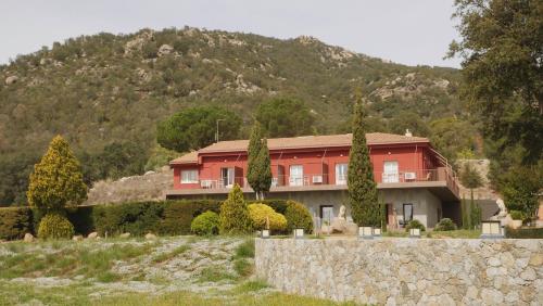 a red house in front of a mountain at Hostal Rural Can Pau in Cantallops