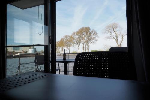 a table and chairs in a room with a view of the water at Houseboat Tiny Griffin in Nieuwpoort